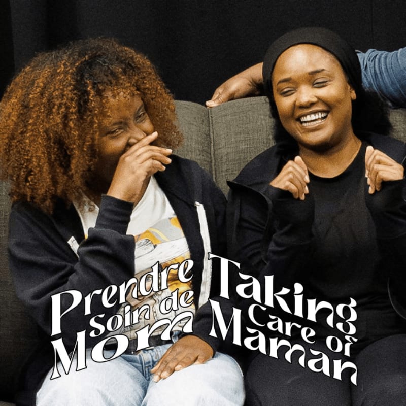Two women laugh on a couch in front of a dark background with text overlaying the image.