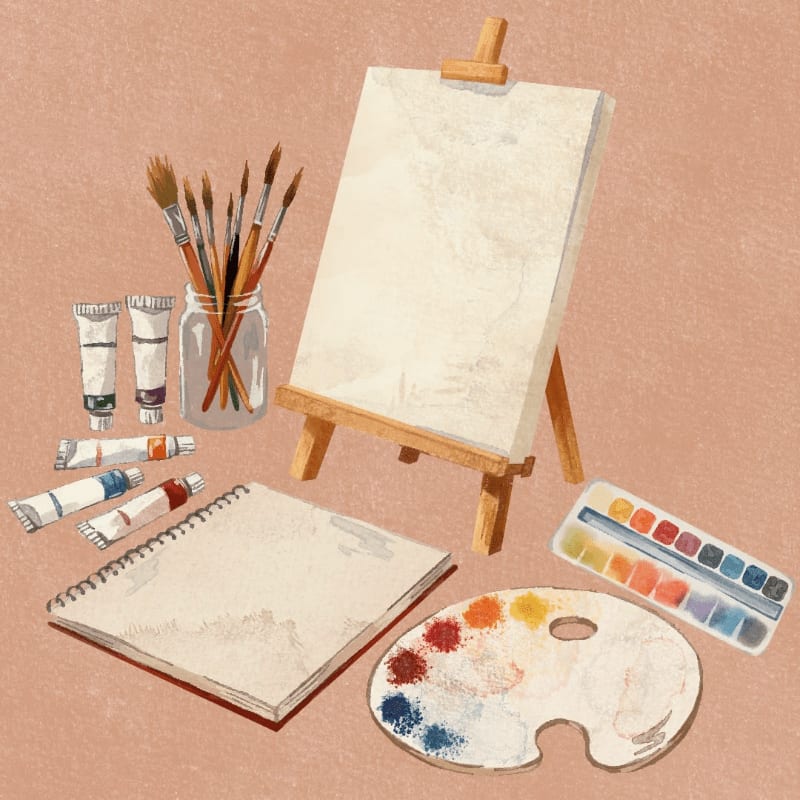 Paintbrushes in a jar and tubes of paint rest on a textured surface in front of a blank canvas on an easel, with a watercolor palette and a sketchbook to the side.