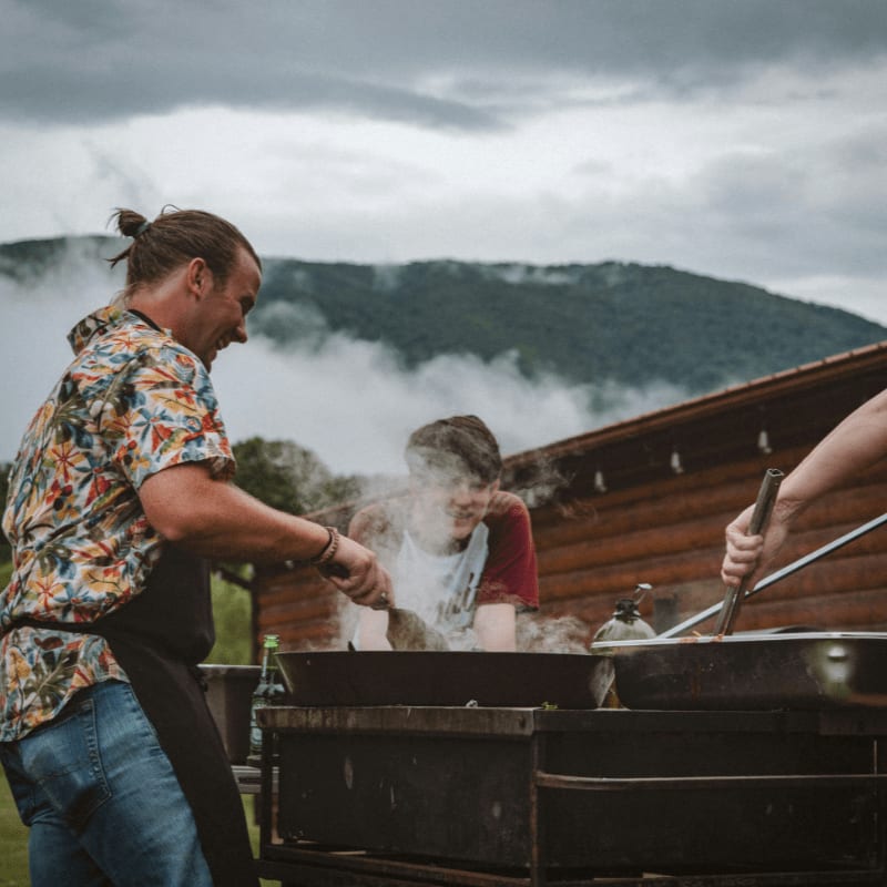 a group of people cooking on a grill outside