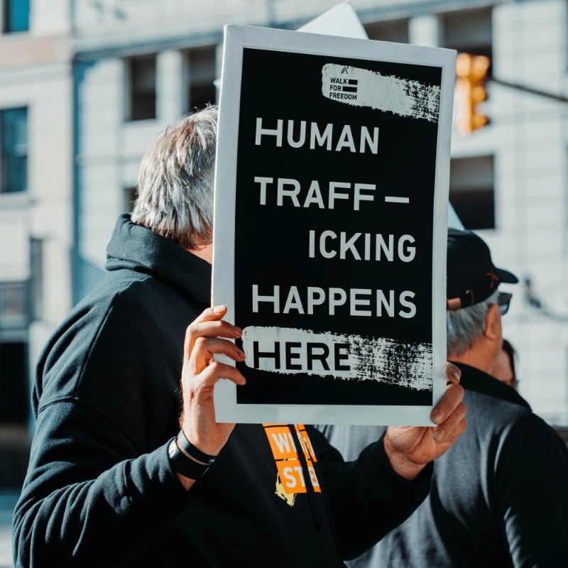 man in black jacket holding black and white quote board