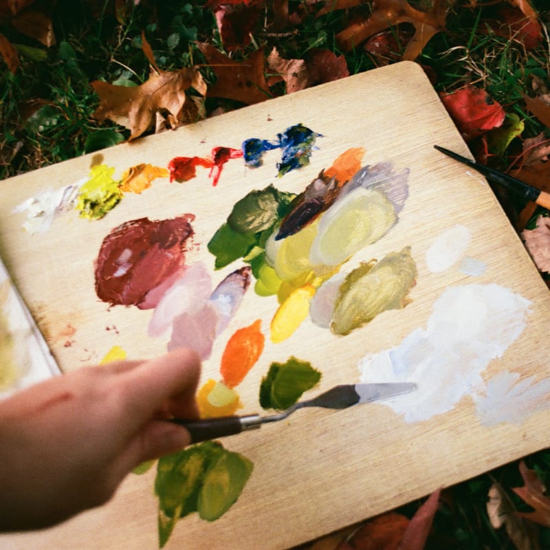 Artist mixes paints on a wooden palette outdoors