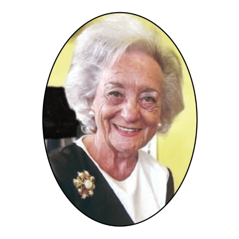 A smiling elderly woman with white hair and a brooch is framed by a yellow and black background.