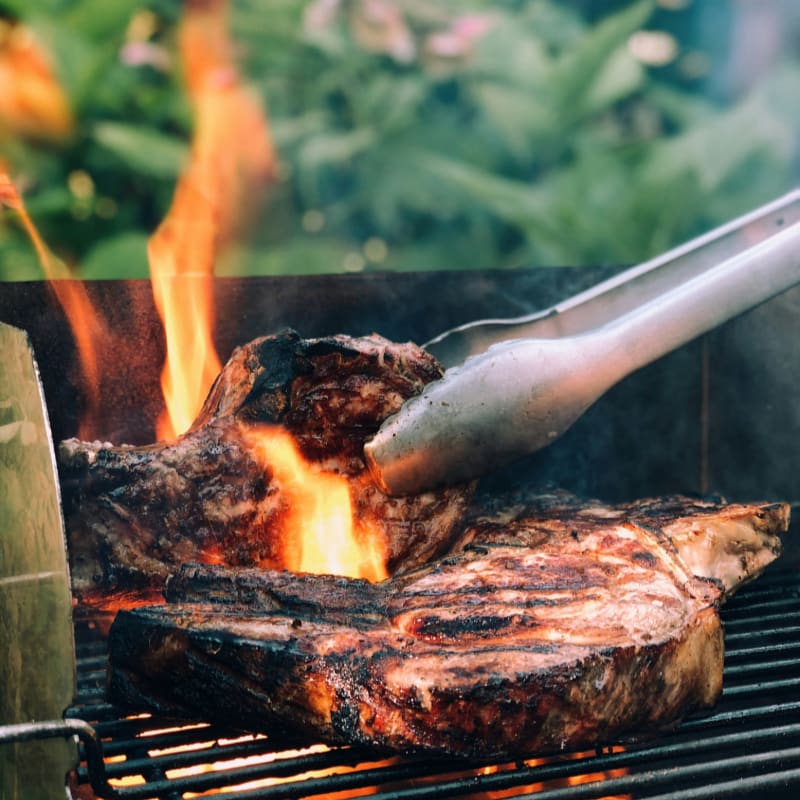 gray metal tong and grilled meat with fire