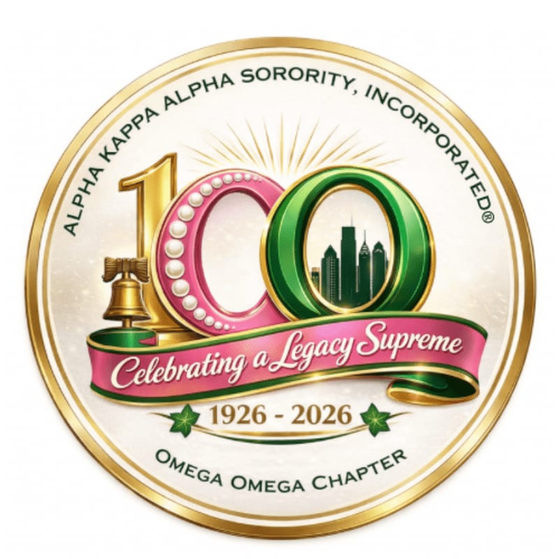A golden circular emblem features the number "100" prominently in the foreground, with a pink ribbon proclaiming "Celebrating a Legacy Supreme" and the years "1926 - 2026," while the background displays a cityscape within a green circle and the text "ALPHA KAPPA ALPHA SORORITY, INCORPORATED" and "OMEGA OMEGA CHAPTER."