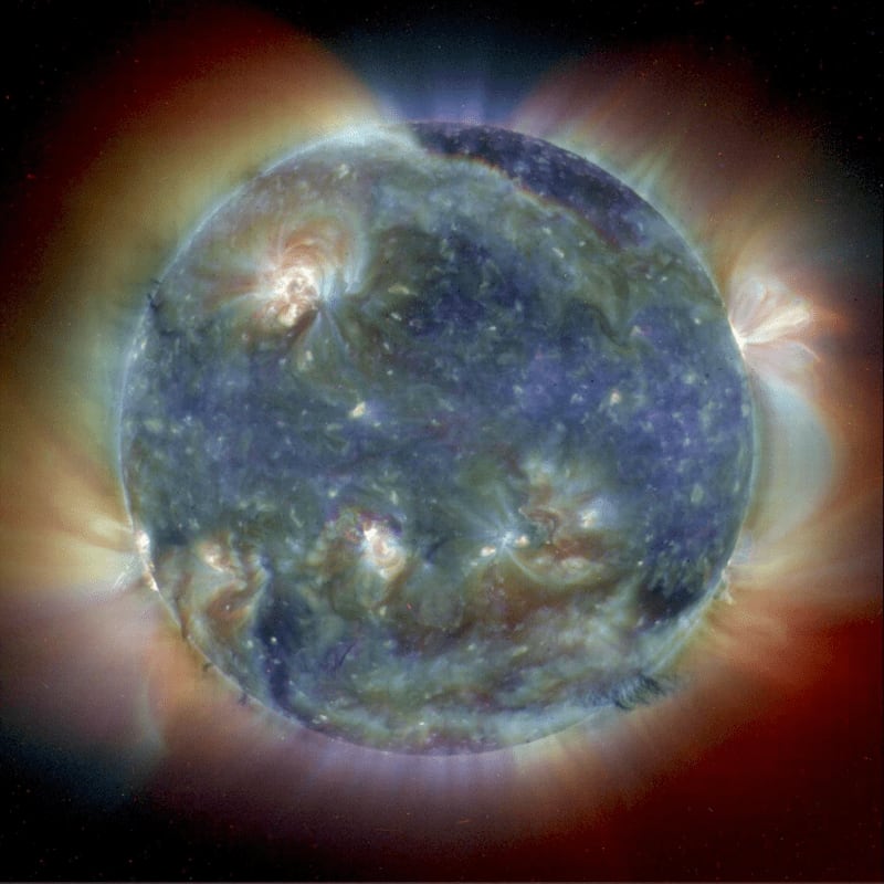 A vibrant, textured sun with glowing prominences erupting from its surface against a dark, cosmic backdrop.