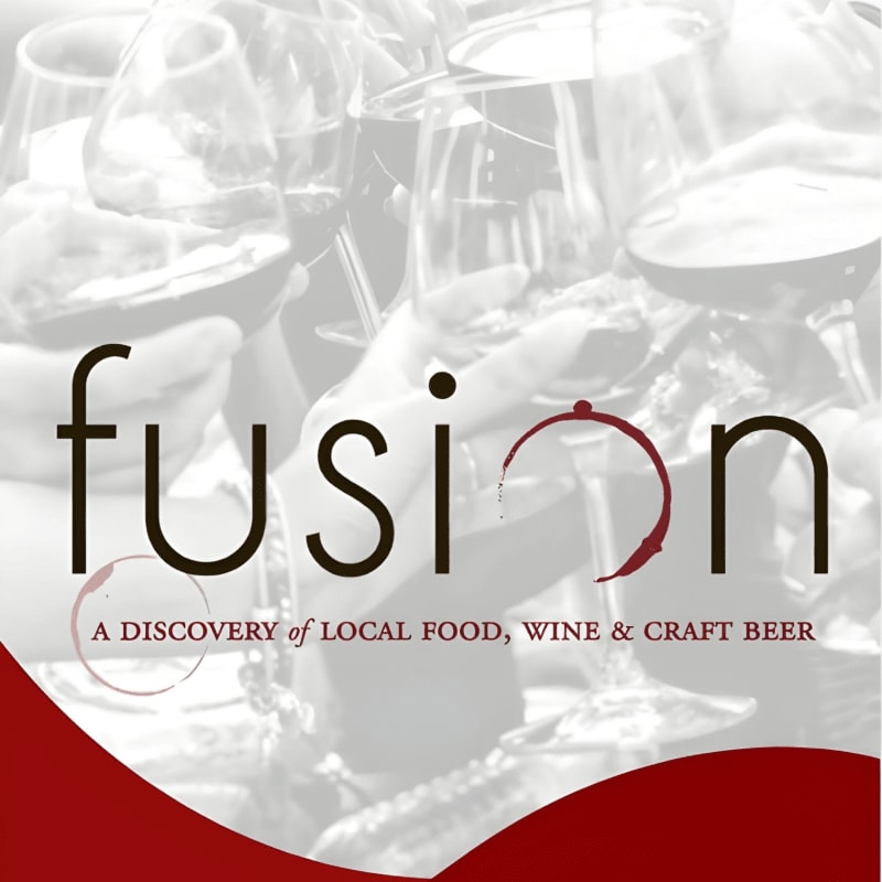 A pile of empty wine glasses fills the foreground, with event details for "fusion" and sponsor logos in the background.