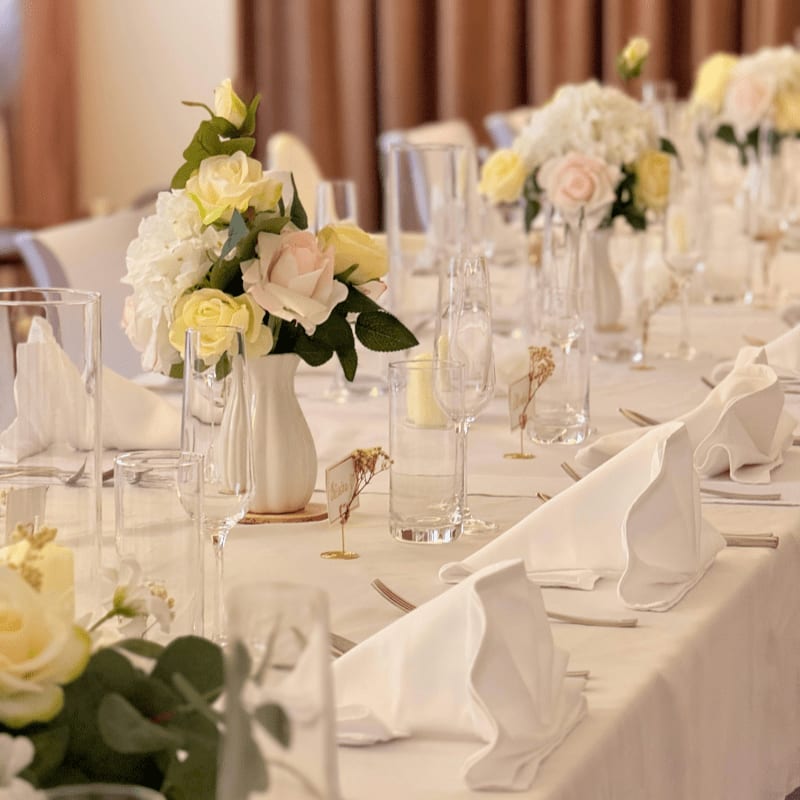 A long dining table set for a wedding with white napkins and floral centerpieces