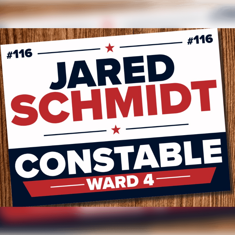 A campaign sign for Jared Schmidt for Constable Ward 4 is displayed on a wooden surface.