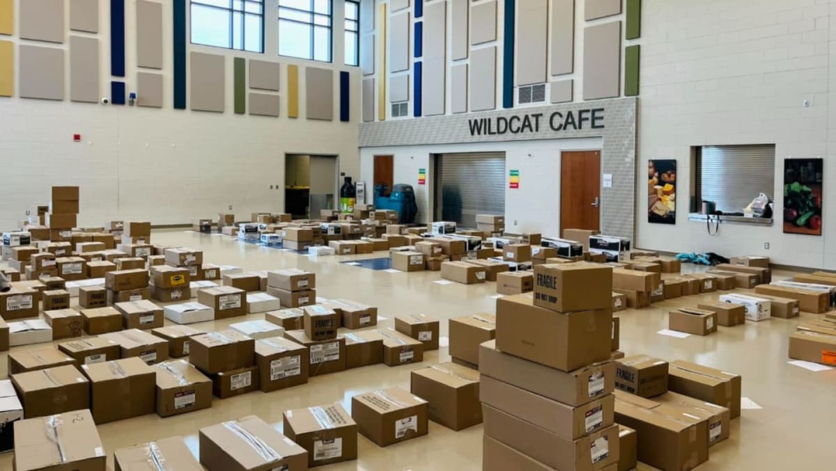 Cardboard boxes are scattered across the floor of a large room with a sign reading "WILDCAT CAFE" in the background.