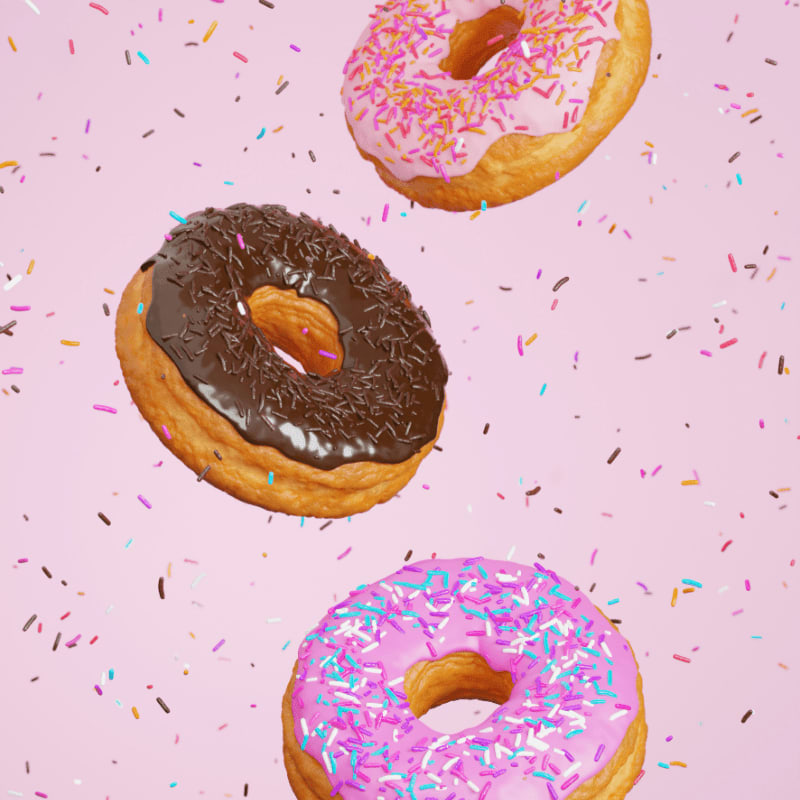 Three floating donuts with chocolate and pink icing and colorful sprinkles on pink