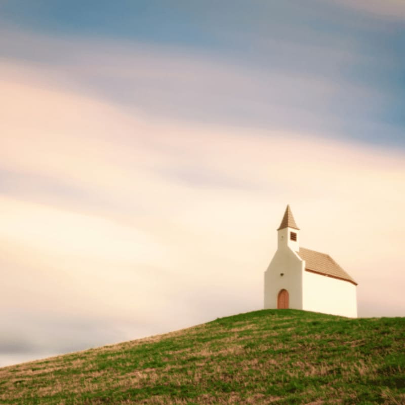 A small church on a hill with a sky background