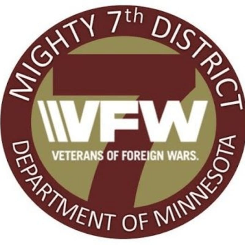 A circular logo with "MIGHTY 7th DISTRICT DEPARTMENT OF MINNESOTA" around the edge, featuring the VFW logo with "VETERANS OF FOREIGN WARS." in the center.