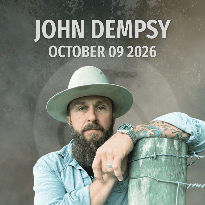 A man with a beard and a hat leans on a fence post in the foreground, with the name "JOHN DEMPSEY" and a date in the background.