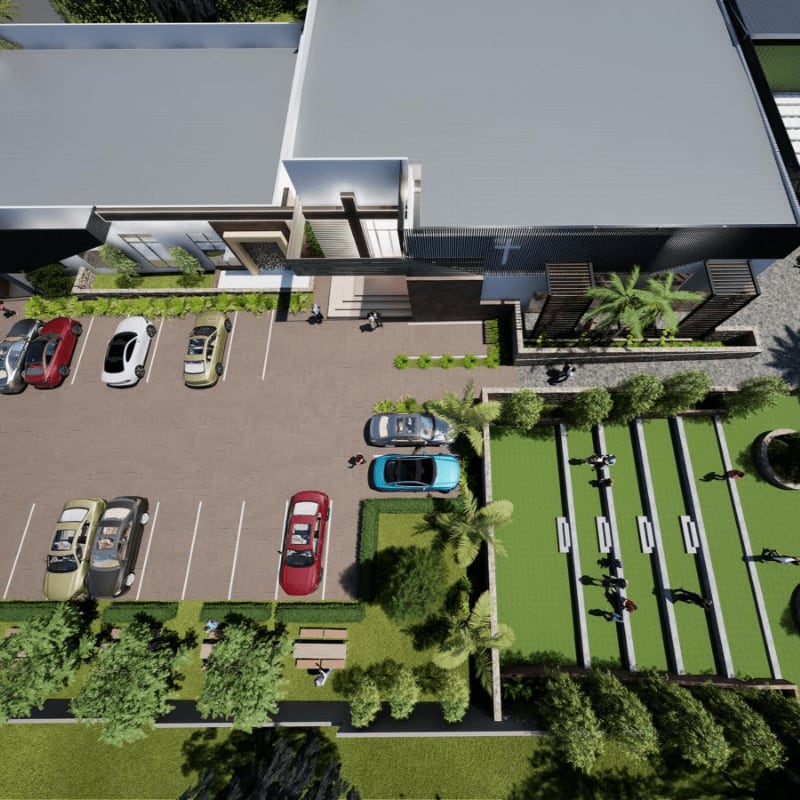 Cars are parked in a lot in front of a modern building with a green recreational area to the right.