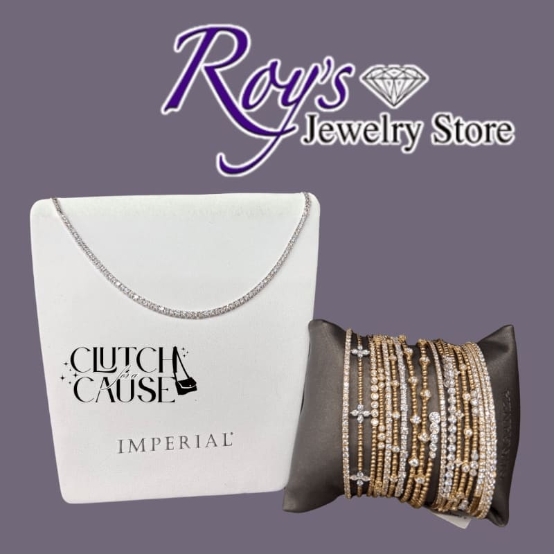 A diamond tennis necklace on a white display stand and a set of gold and diamond bracelets on a grey cushion sit against a purple background with the "Roy's Jewelry Store" logo.