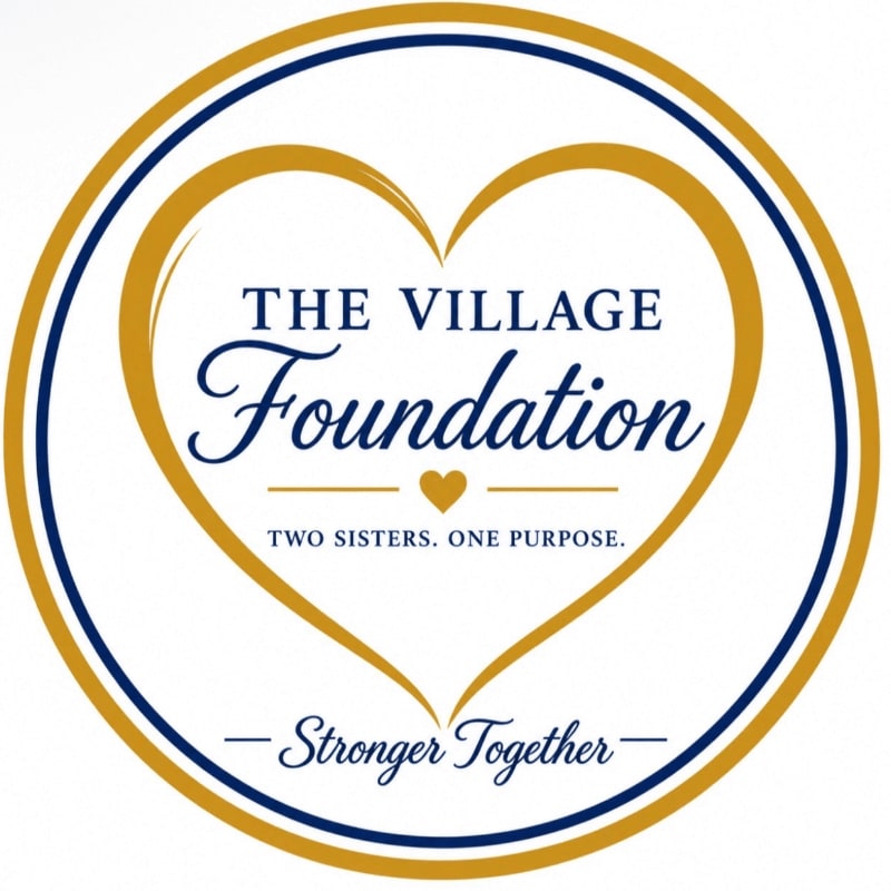 A circular logo featuring a gold heart and the text "THE VILLAGE Foundation" set against a plain white background.