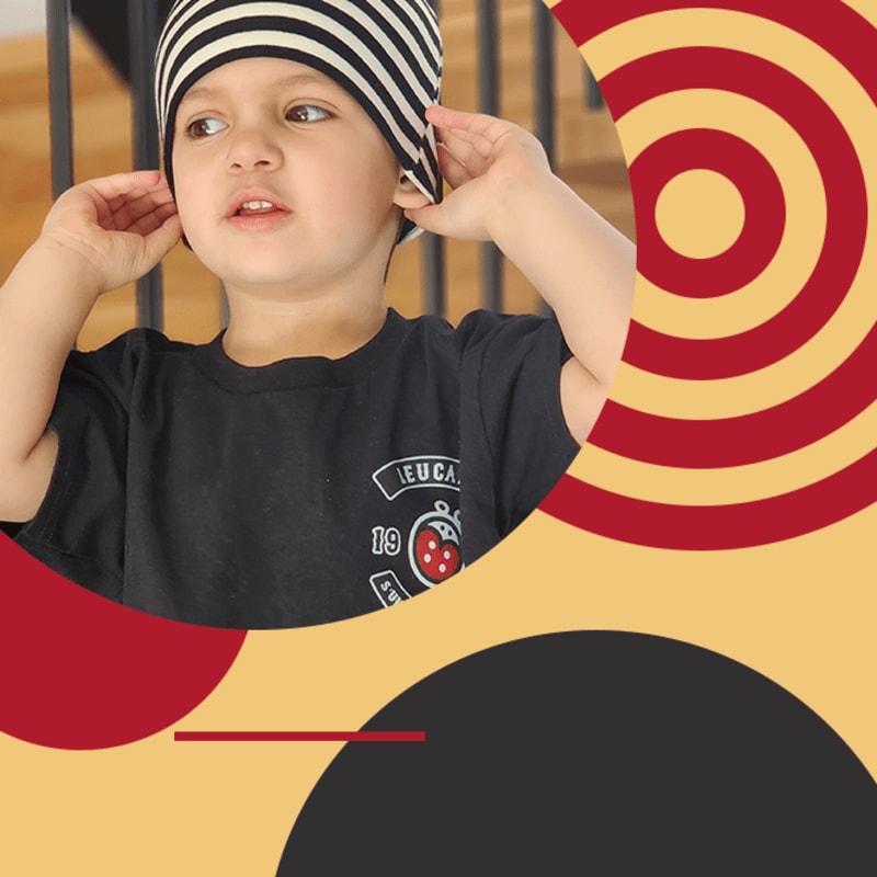 A young child wearing a striped hat and black t-shirt is positioned against a background of red and black geometric shapes.