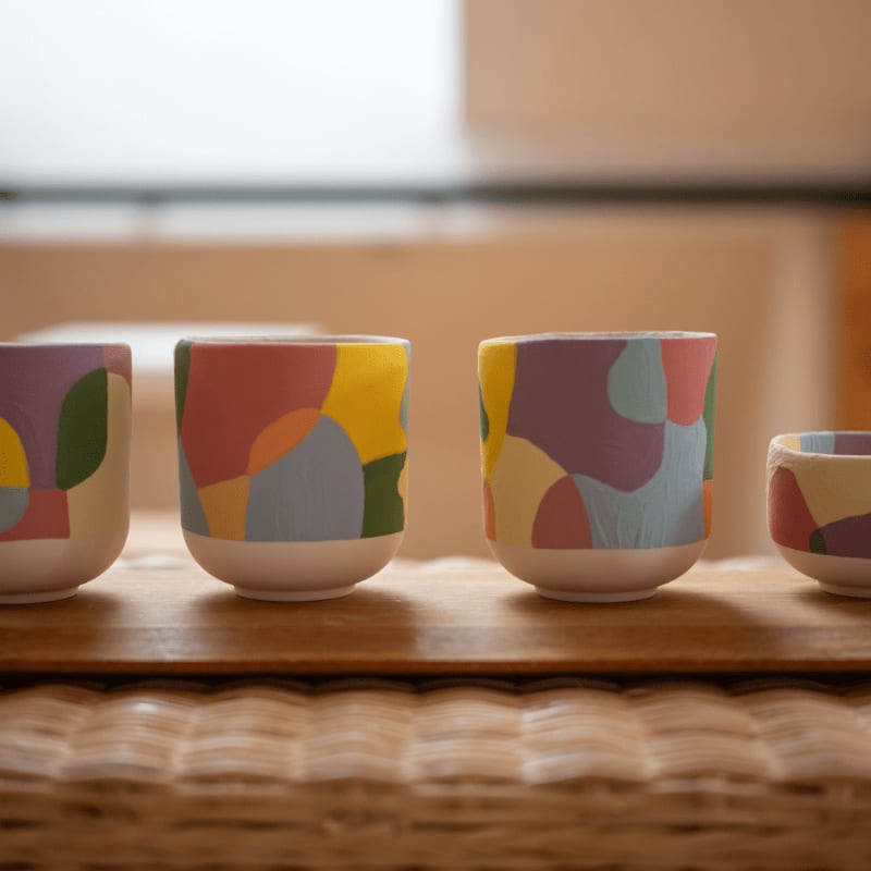 Four colorful abstract ceramic cups on a wooden surface