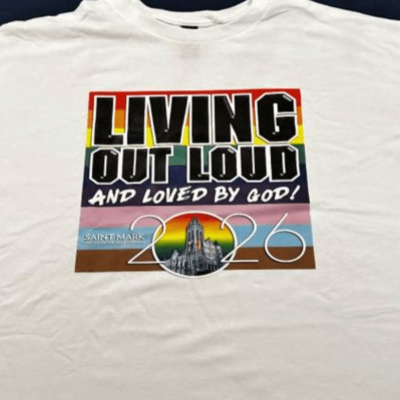 A white t-shirt features a colorful graphic with the text "LIVING OUT LOUD AND LOVED BY GOD!" and the year "2026" over a rainbow background.