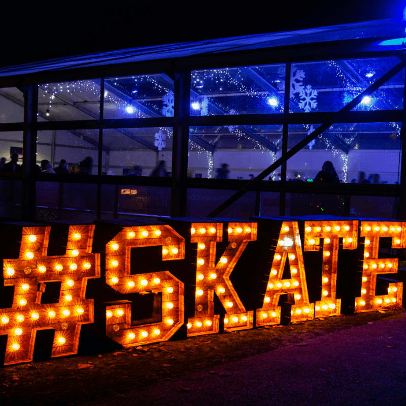 a lighted sign that says skate in front of a building