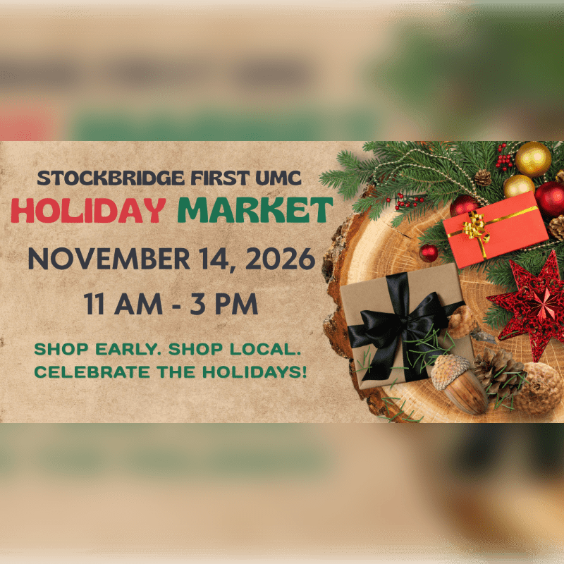 An announcement for the Stockbridge First UMC Holiday Market on November 14, 2026, is set against a blurred background with festive gifts and greenery on a wooden slice in the foreground.