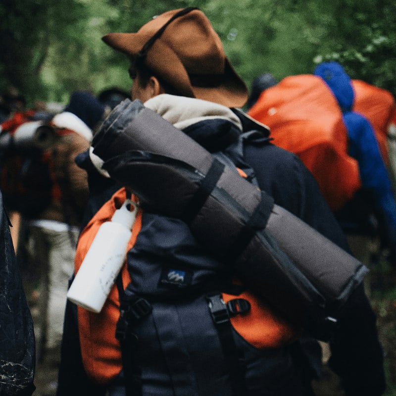 man carrying black sleeping bag and backpack