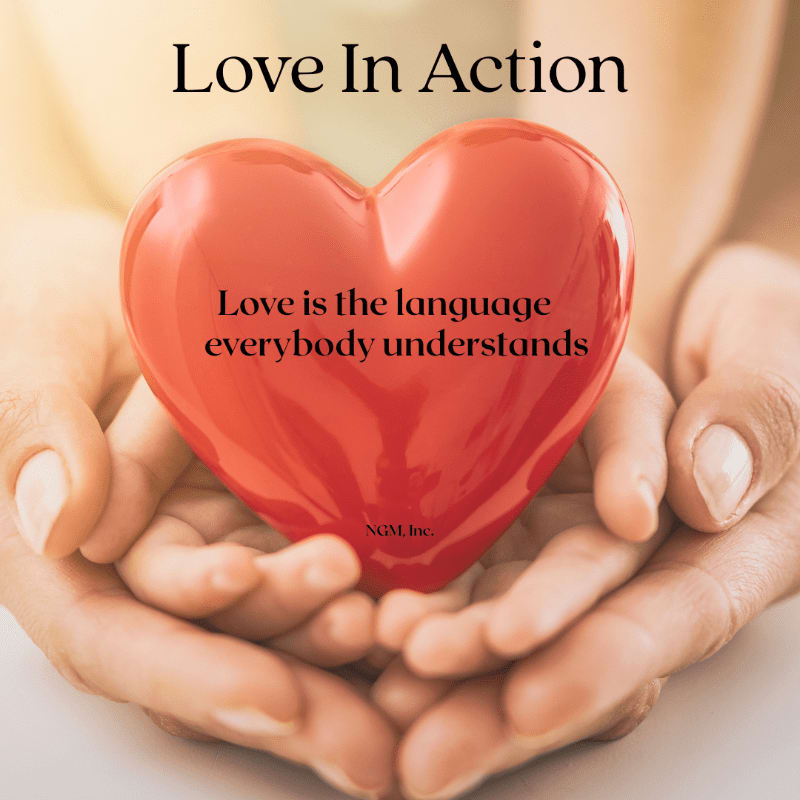 A glossy red heart with inspirational text rests in a pair of cupped hands against a soft, blurred background.