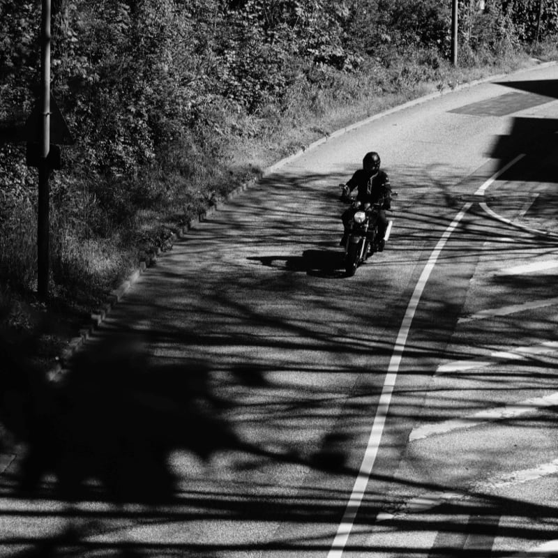 Motorcyclist rides on a winding road with shadows