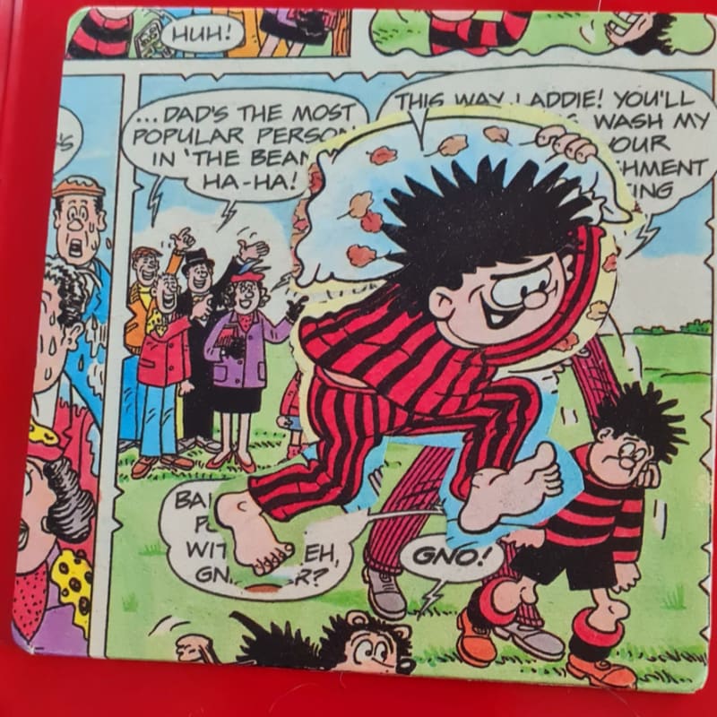 A cartoon character in red and black striped pajamas runs toward a smaller child in the foreground, while a group of people stands in the background.