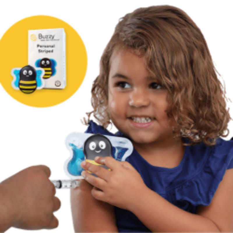 A young girl in a blue shirt holds a bee-shaped vibration device on her arm while receiving a shot, with a product box displayed in a yellow circle in the background.