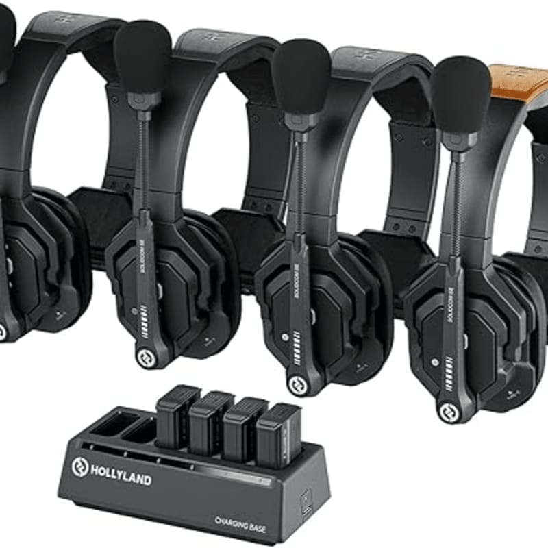 A black Hollyland charging base sits in the foreground before a row of professional wireless headsets.