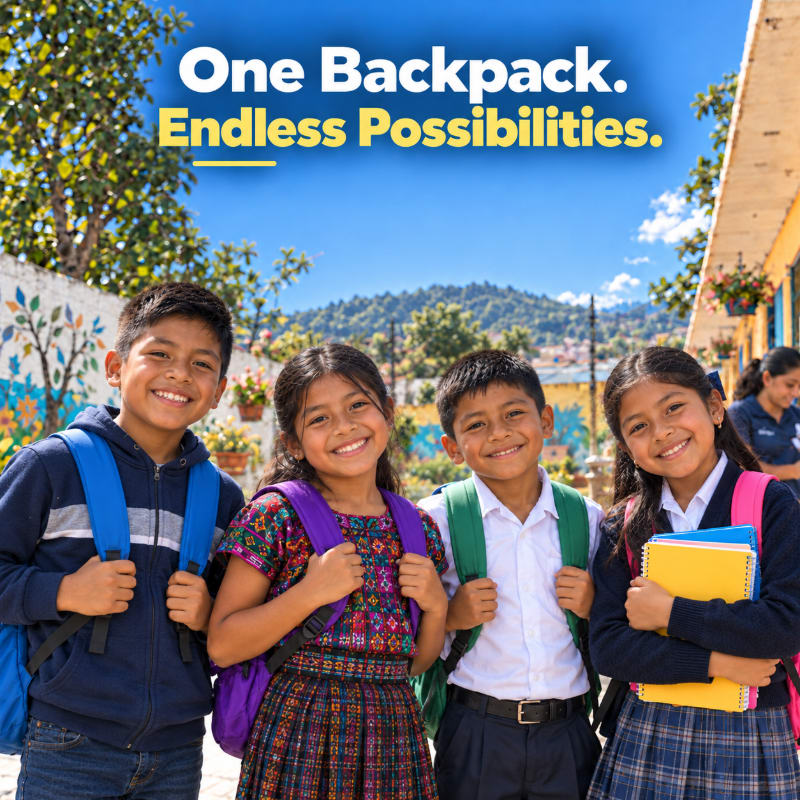 Four smiling children with backpacks stand in the foreground against a background of a sunny town and distant mountains.