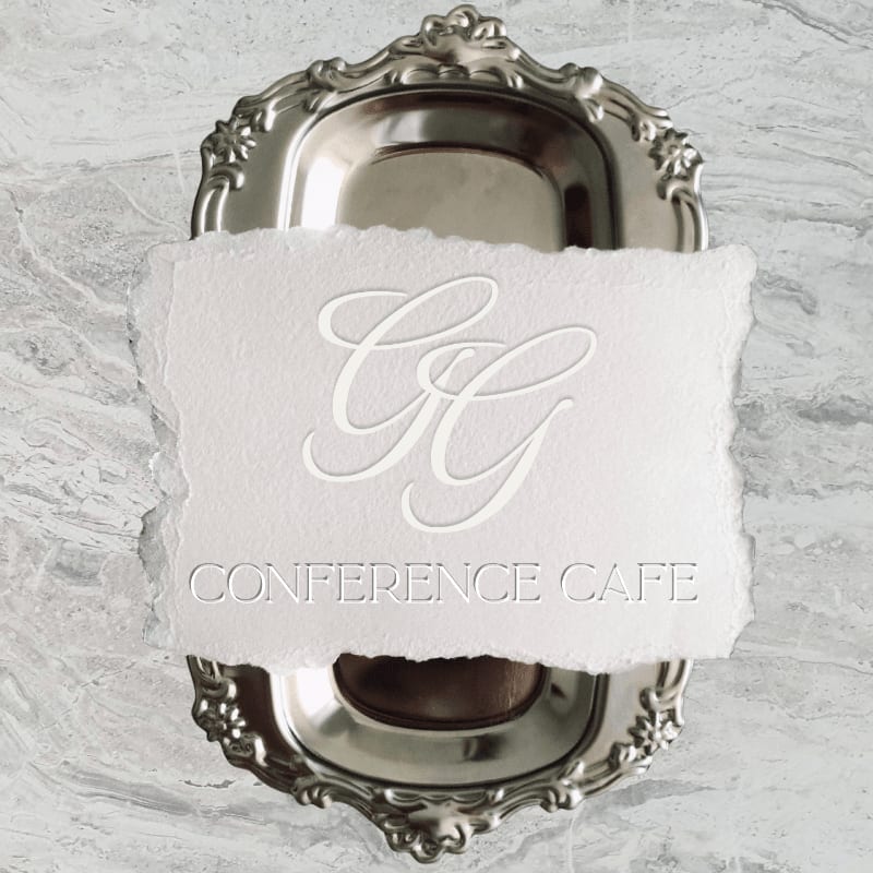 A white torn piece of paper with "CG CONFERENCE CAFE" embossed on it rests atop an ornate silver tray against a marbled grey background.