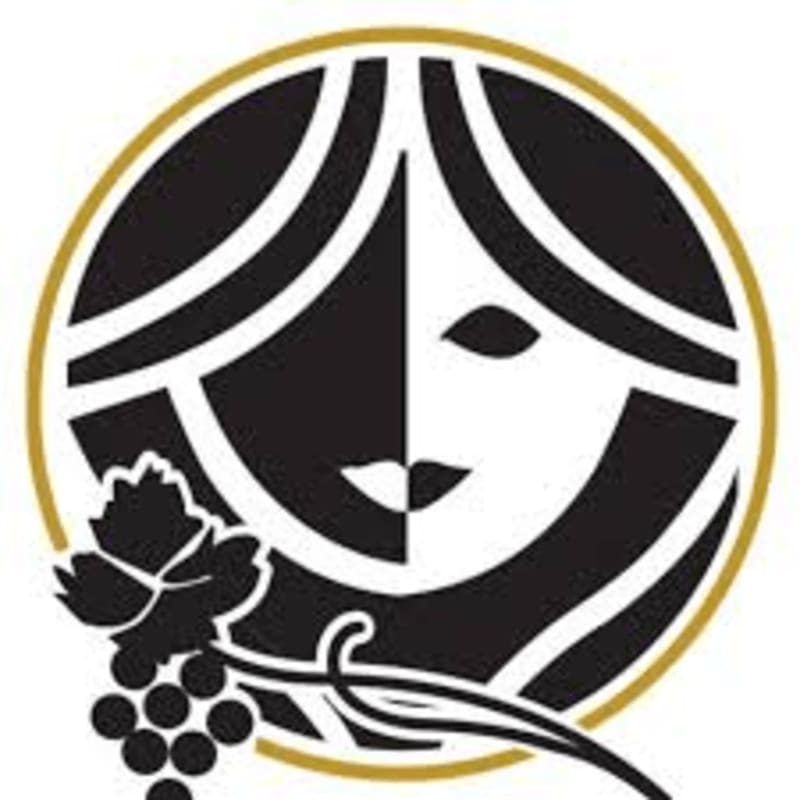 A stylized black and white face is centered within a gold circular border, with a bunch of grapes and a vine in the foreground against a plain white background.