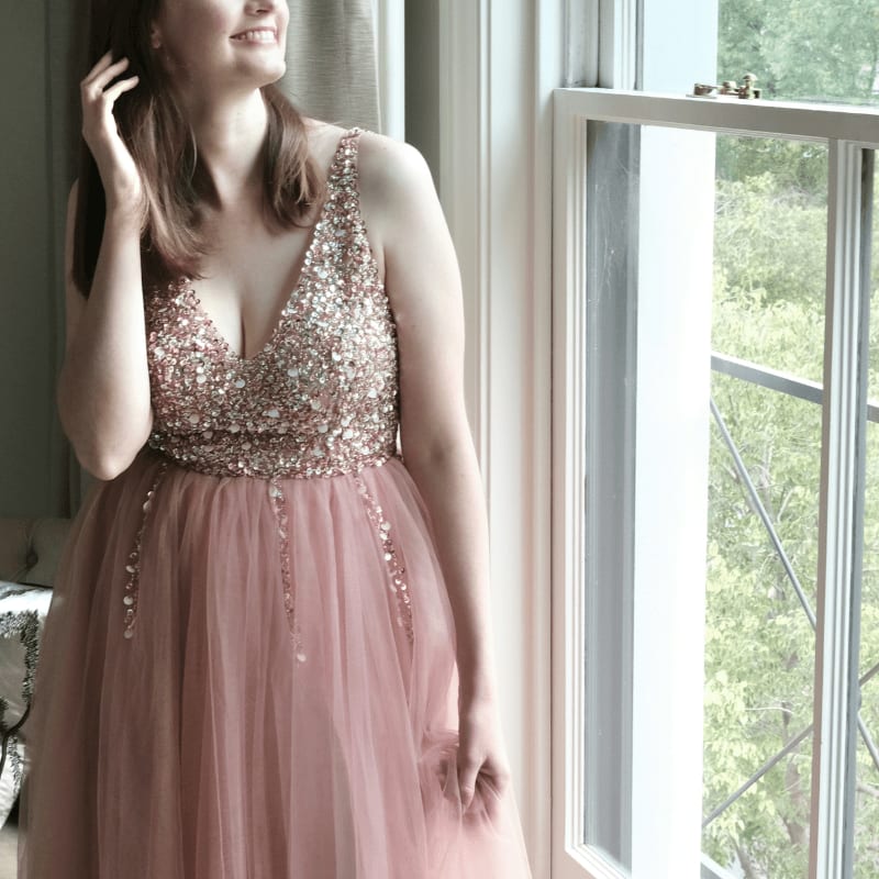 a woman in a pink dress standing next to a window