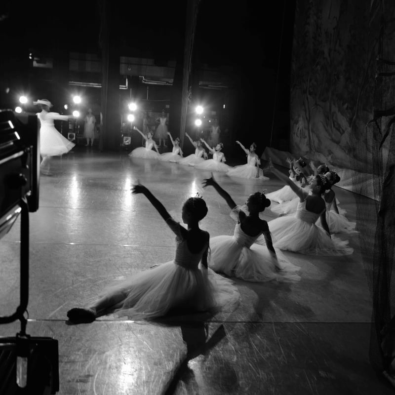 Ballet dancers in tutus perform on stage with spotlights