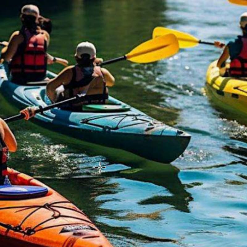 Three people in colorful kayaks paddle down a calm river surrounded by lush green marshland under a cloudy sky.