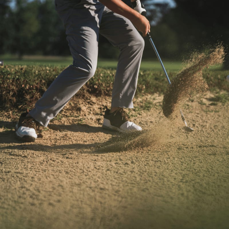 person in black t-shirt and white pants holding golf club
