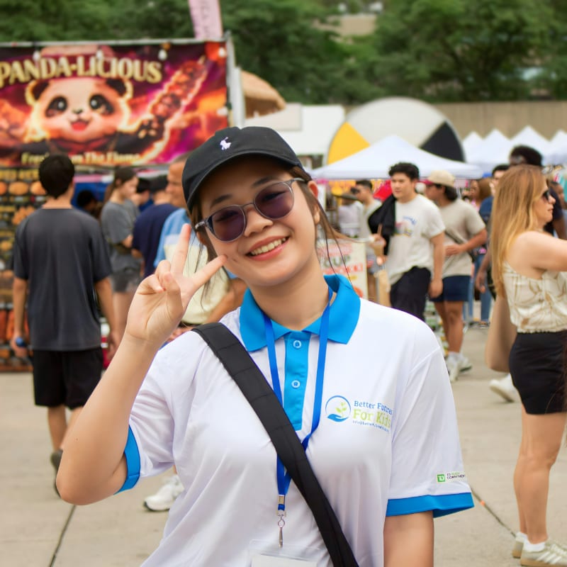 Young woman smiles, makes peace sign at outdoor event