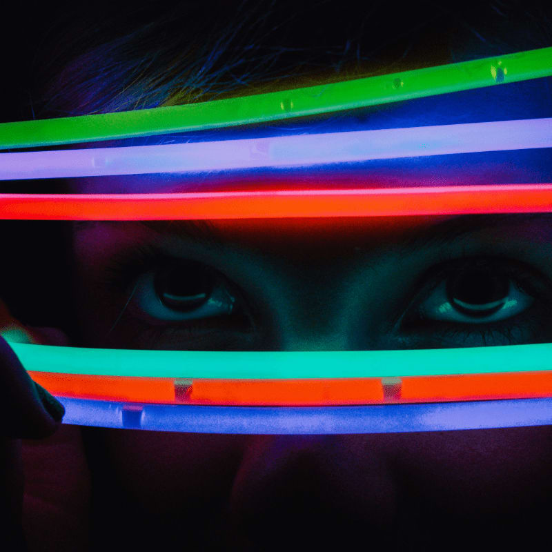 a person holding a neon light up in front of their face