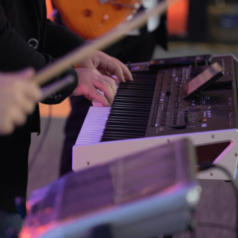 a person playing a keyboard with a guitar in the background