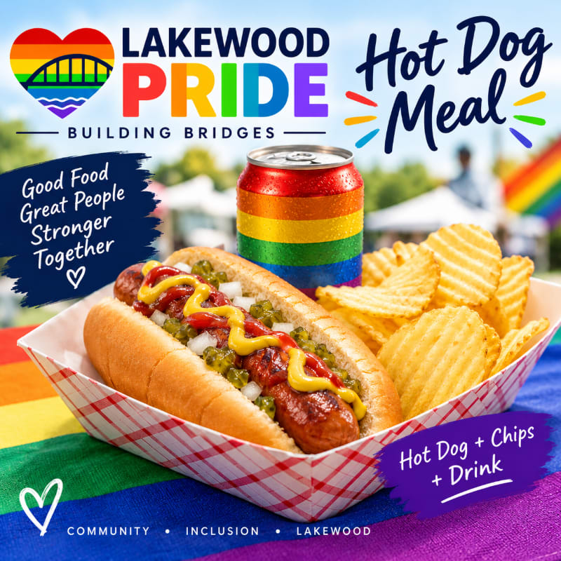 A hot dog with toppings and potato chips in a checkered tray sit in the foreground next to a rainbow-colored can, set against a blurred outdoor event background with Pride branding.