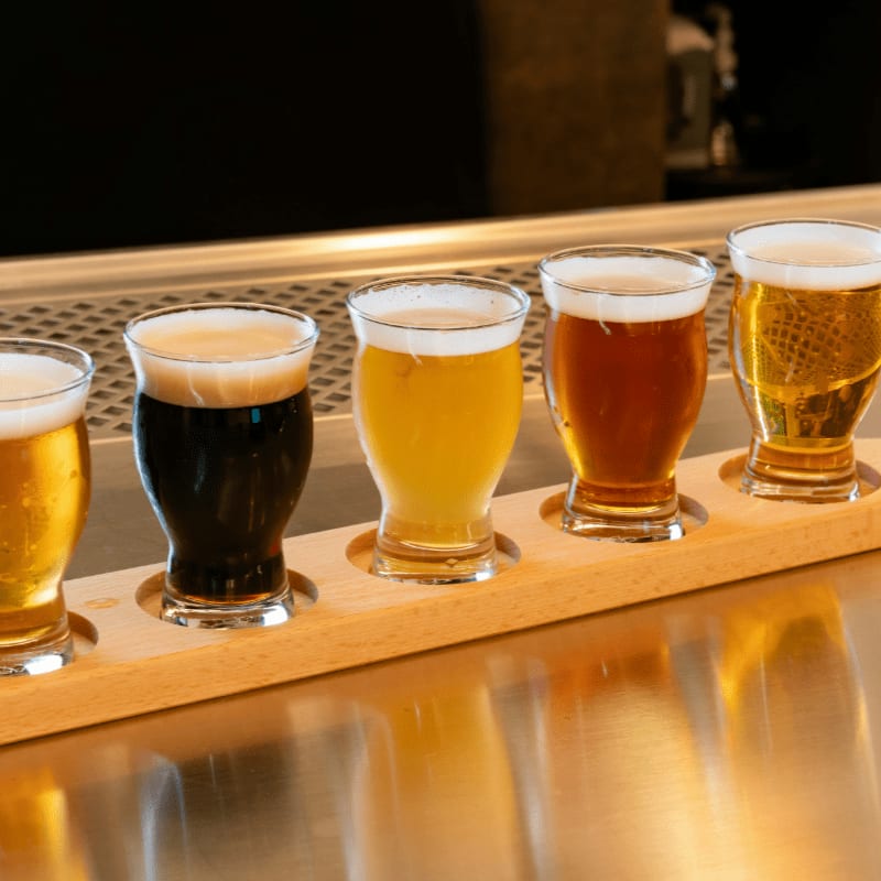 a row of beer glasses sitting on top of a wooden tray