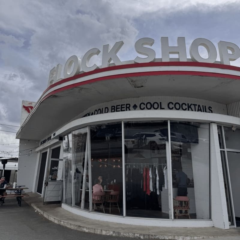 A curved storefront with a "BLOCK SHOP" sign and large glass windows sits beneath a cloudy sky.