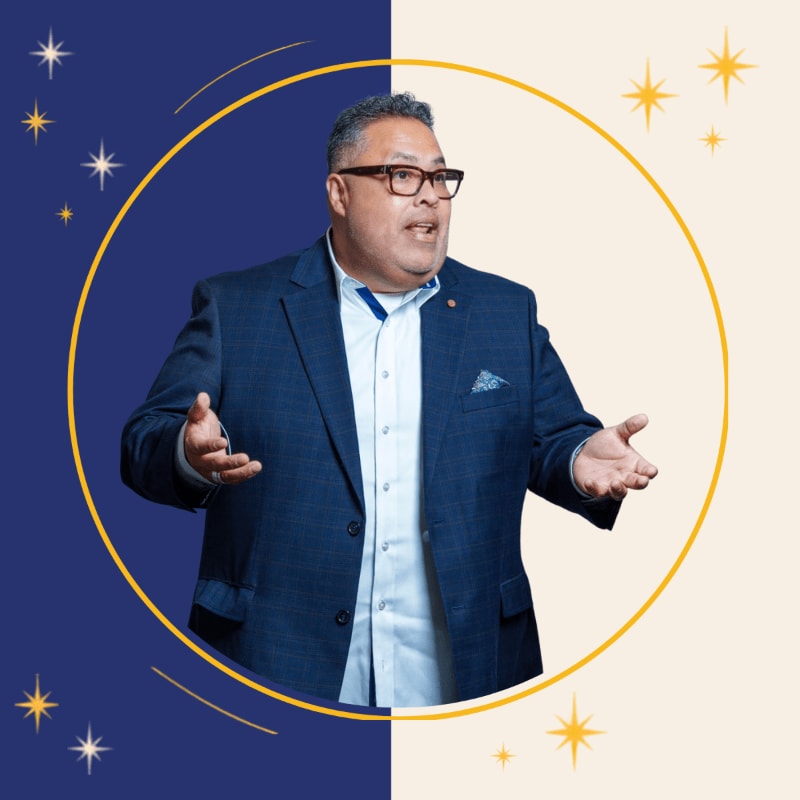 A man in a blue blazer and glasses gestures with open hands inside a yellow circle, set against a split blue and cream background adorned with stars.