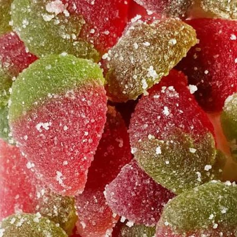 Sugar-coated red and green strawberry candies fill the foreground and extend into the background.