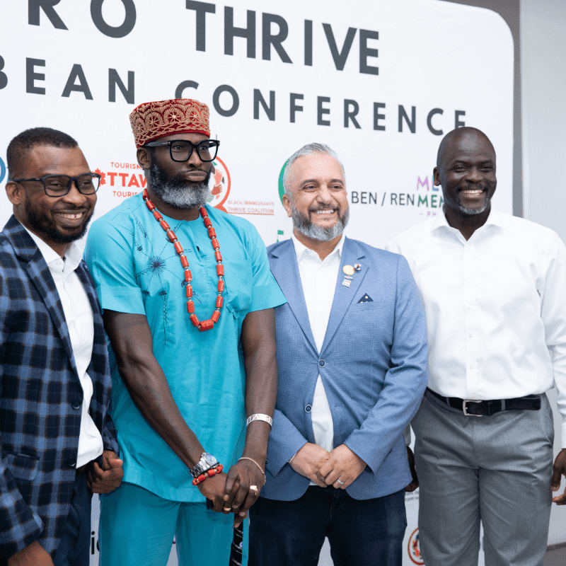 Four men pose for a photo in front of a white banner that reads "THIVE CARIBBEAN CONFERENCE."