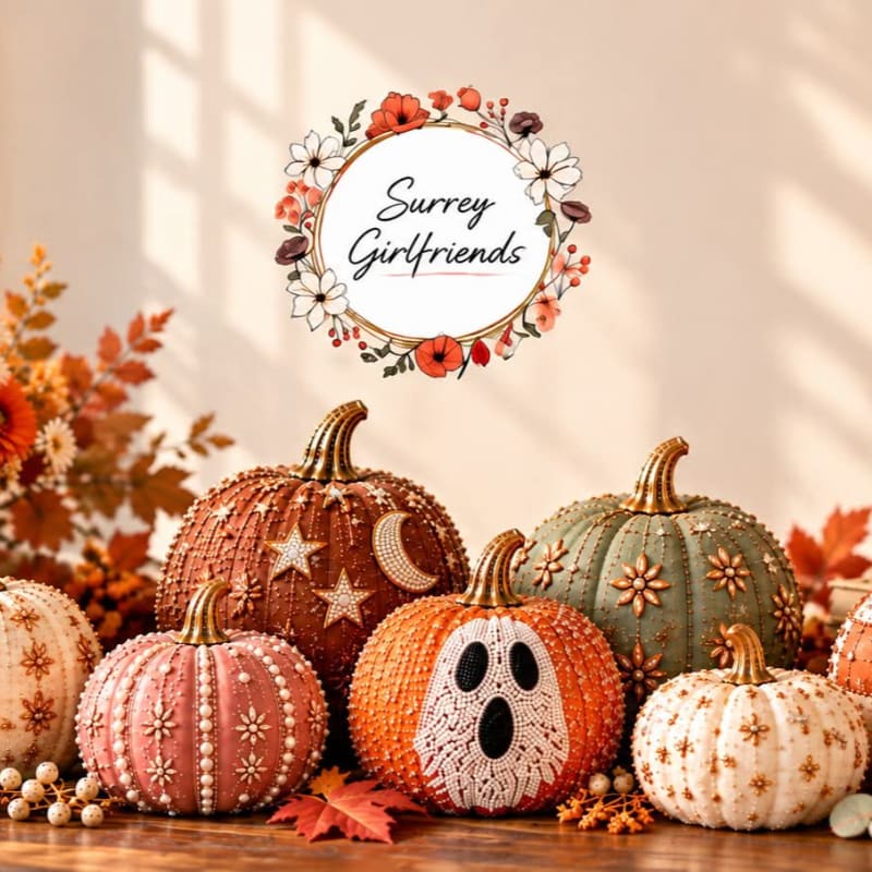 Beaded decorative pumpkins sit in the foreground against a soft-lit wall featuring a floral circular logo.