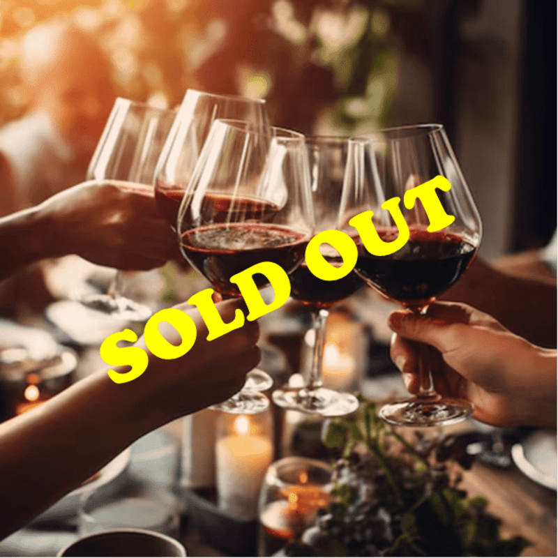 Hands toast with glasses of red wine in the foreground, while a blurred dining setting with candles and people fills the background.