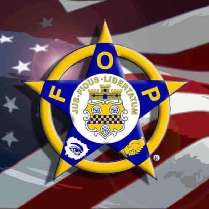 A gold and blue Fraternal Order of Police star emblem is centered over a blurred American flag background.